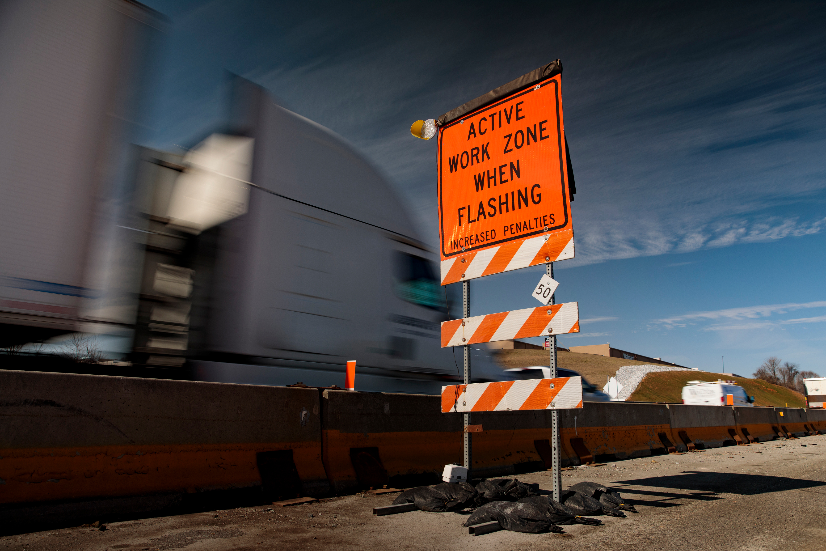 Truck passing a work zone sign that reads "Active Work Zone When Flashing Increased Penalties"